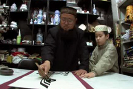 Ma Yi Ping is teaching his son the art of calligraphy [Al Jazeera]