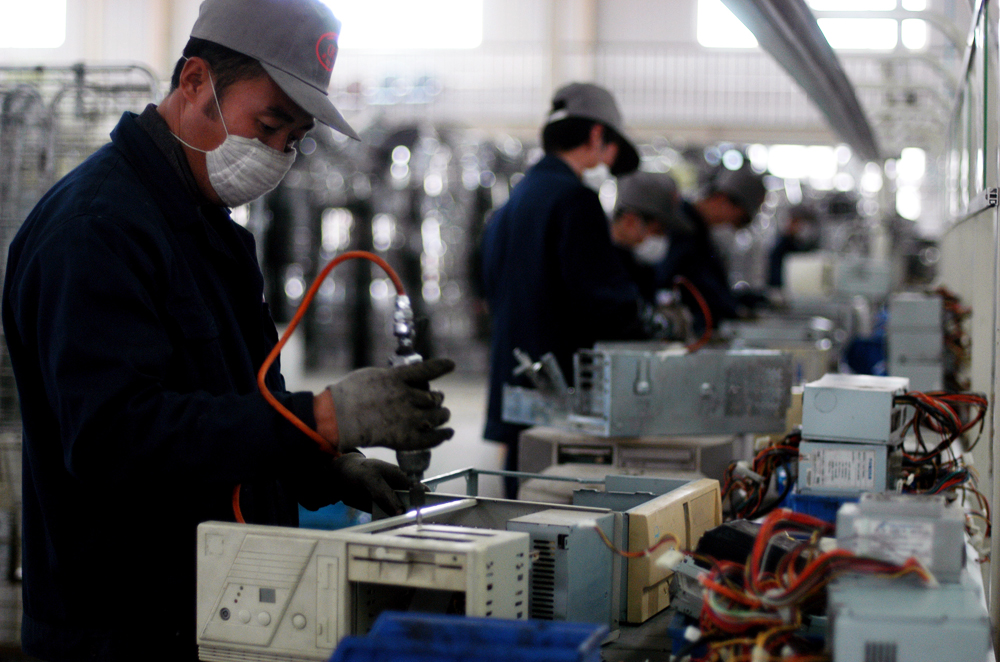 China e-waste gallery - Chinese worker deconstructing a motherboard