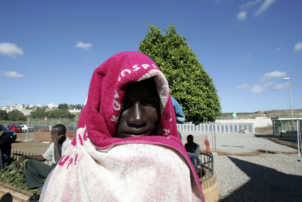 An African migrant waits in line for his turn for a shower outside at the CETI