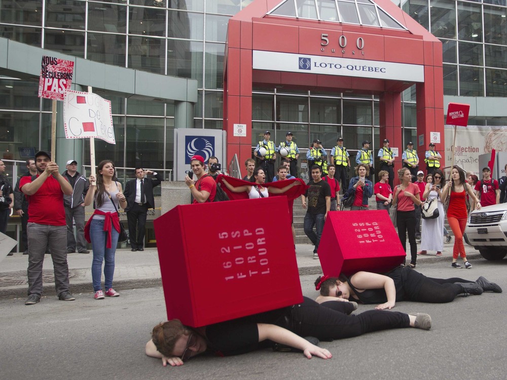 Students lie down in front of Loto Quebec as they protest against tuition hikes in downtown Montreal
