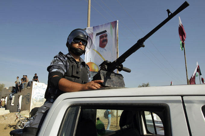 A poster bearing the image of Qatar''s leader Sheik Hamad bin Khalifa al-Thani watches over a member of Hamas security forces in Rafah