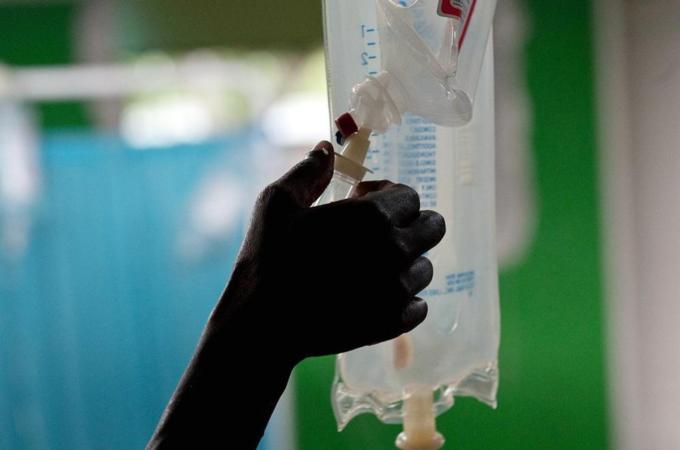 A nurse adjusts an IV drip in a ward ful