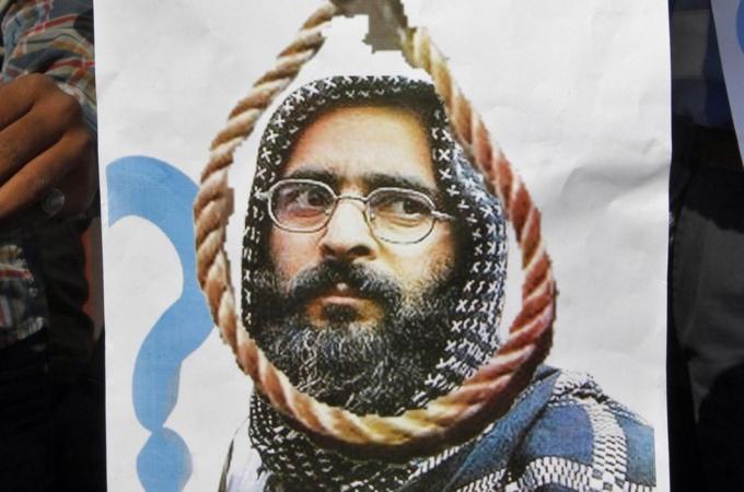 A member of a social group holds a placard with a picture of Afzal Guru before burning it during a protest in Ahmedabad