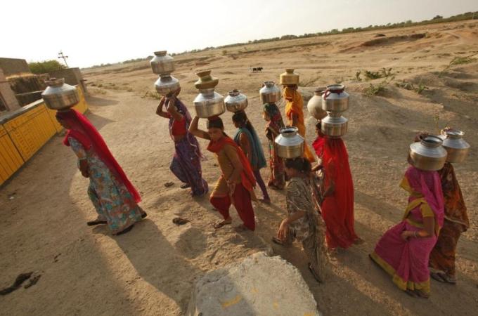 Women carry metal pitchers containing drinking water to their homes at Merta district in Rajasthan