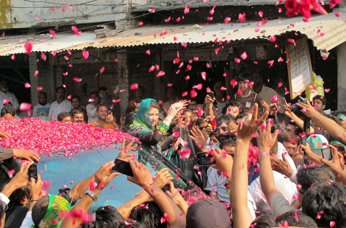 Maryam Nawaz is covered in rose petals as she encourages voters in Lahore [Asad Hashim/Al Jazeera]