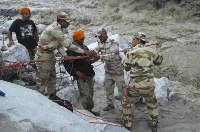 The Indo-Tibetan Border Police personnel rescue stranded people across a flooded river after heavy rains in Uttarakhand