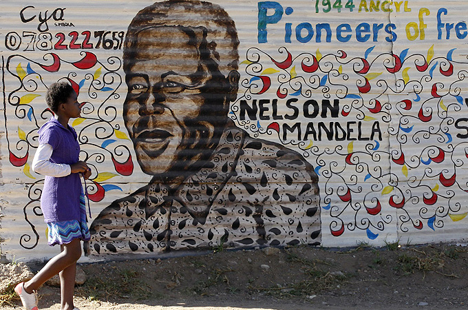 A boy walks past a mural of Nelson Mandela.