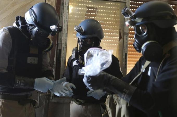 A UN chemical weapons expert holds a plastic bag containing samples from one of the sites of an alleged chemical weapons attack in Ain Tarma Syria