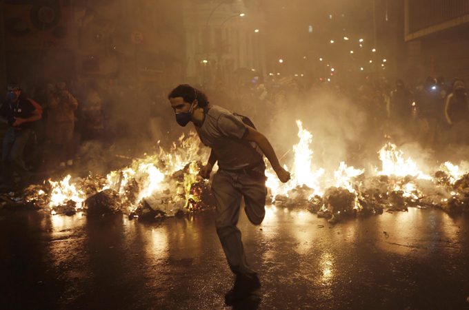 A demonstrator from the group called Black Bloc runs outside the Municipal Assembly during a protest supporting a teachers' strike in Rio de Janeiro [Reuters]