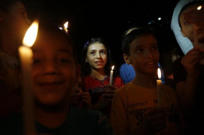 Palestinian children light candles next the rubble of a destroyed building in Gaza City on August 27, 2014 after a long-term truce took hold following a deal hailed by Israel and Hamas as 'victory' in