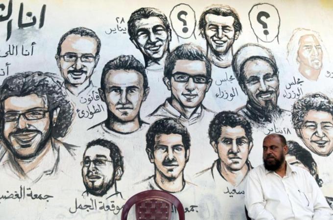 A man sits in front of a mural of people who died during Egypt's revolution at Tahrir Square in Cairo [Reuters]