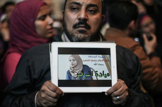 An Egyptian man holds the picture of Egyptian journalist Mayada Ashraf, 23, during a protest over her killing [Getty Images]