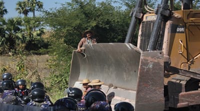 Farmers confront an earth mover, owned by the Chinese mining company in northwestern Myanmar in December [The Associated Press]