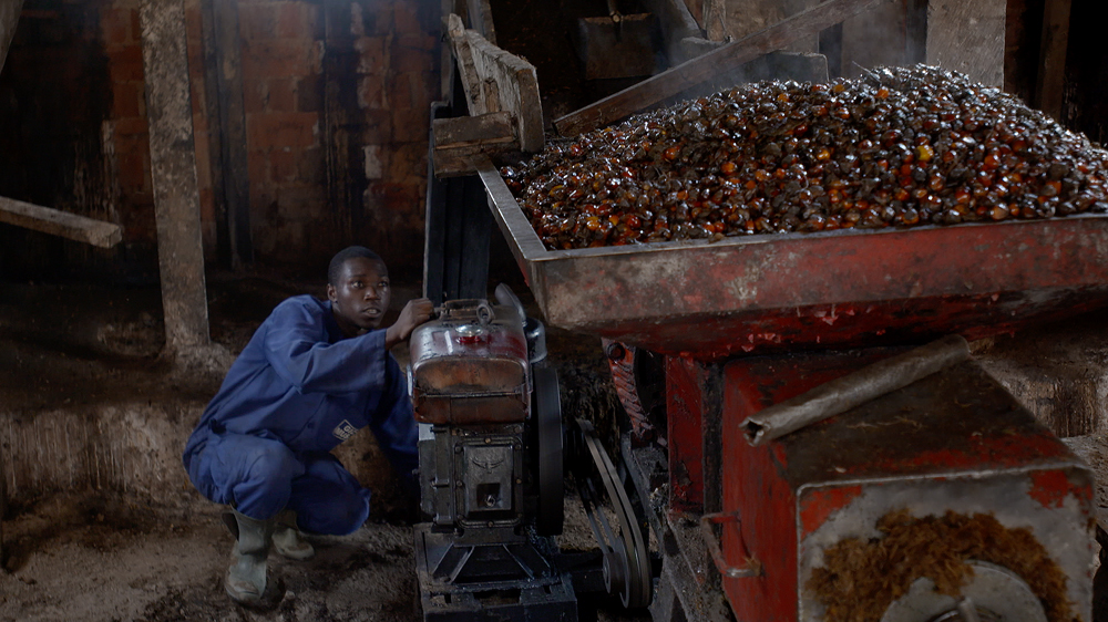 Artisanal mill worker on Jean-Paul Ndenga's 'smallhold' farm [Hugh Hartford / Al Jazeera]