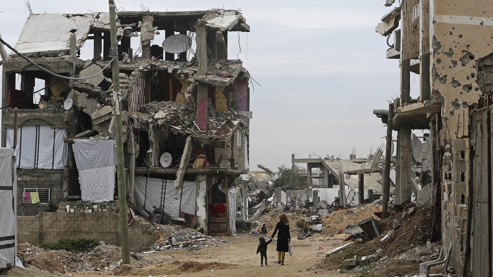 Palestinian children walk between the rubble of buildings which were destroyed during the summer 2014 Israel-Hamas war, in Gaza City [AP]