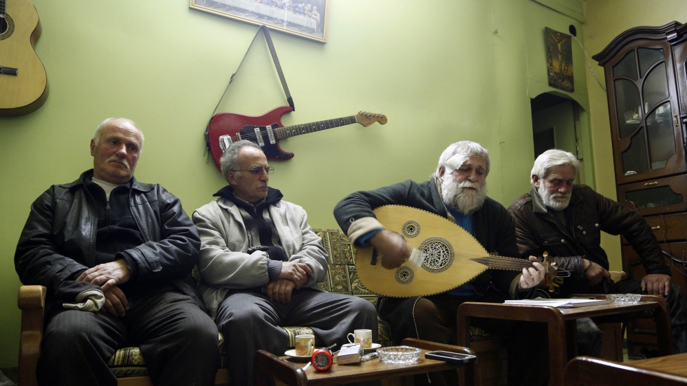 Ibrahim Dawoud plays music on an Oud next to his brother and neighbors inside their home in the ancient Christian quarter of Bab-Touma in Damascus
