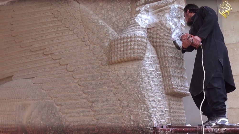 An ISIL militant uses a power tool to destroy a winged-bull Assyrian protective deity at the Ninevah Museum in Mosul, Iraq [AP]