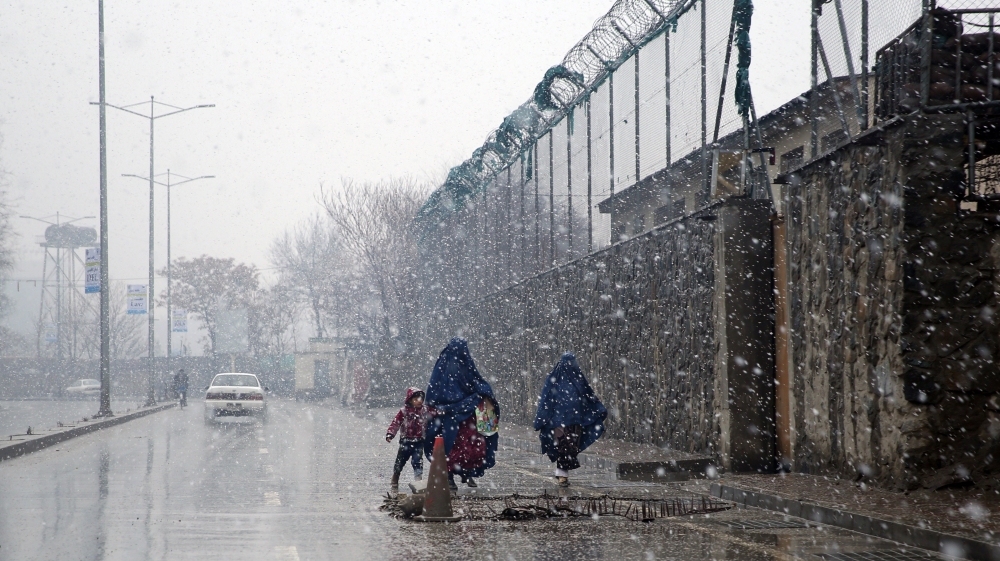 Burqa-clad Afghan women and a child walk during a snow storm in Kabul, Afghanistan [AP]