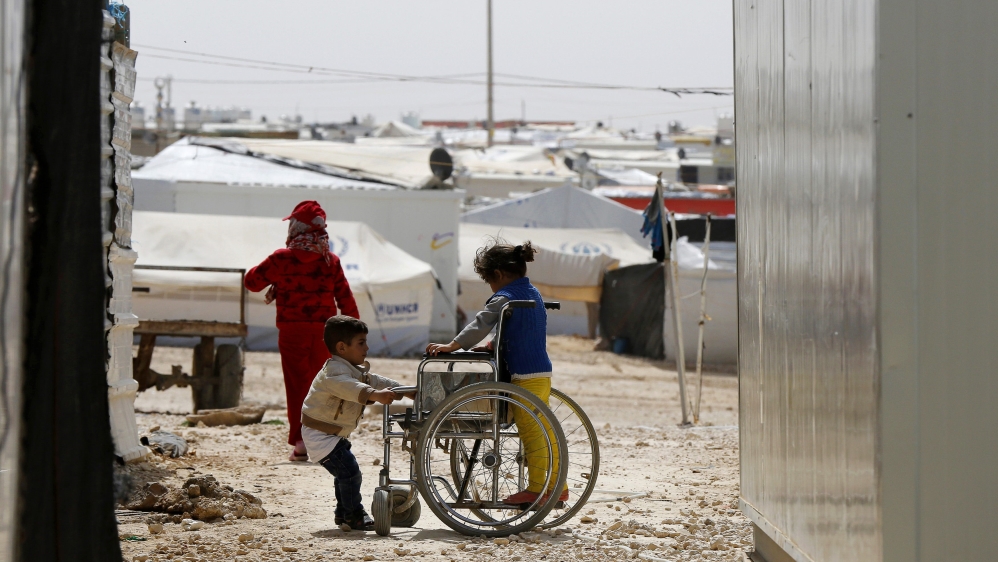 Syrian refugee children play with a wheelchair at the Al Zaatari refugee camp in Mafraq
