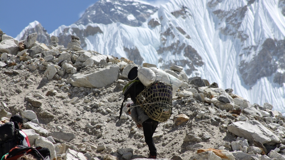 A porter ascends towards Everest Base Camp with Mount Everest seen in the background at Gorakshep, Nepal [AP]