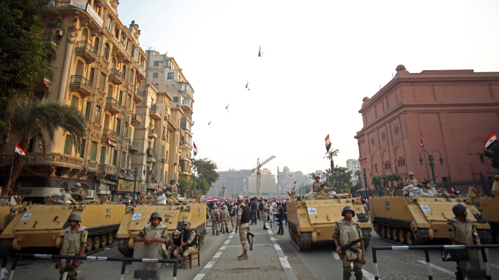 Egyptian military helicopters fly overhead as army soldiers stand guard at an entrance to Tahrir Square, in Cairo, Egypt [AP]