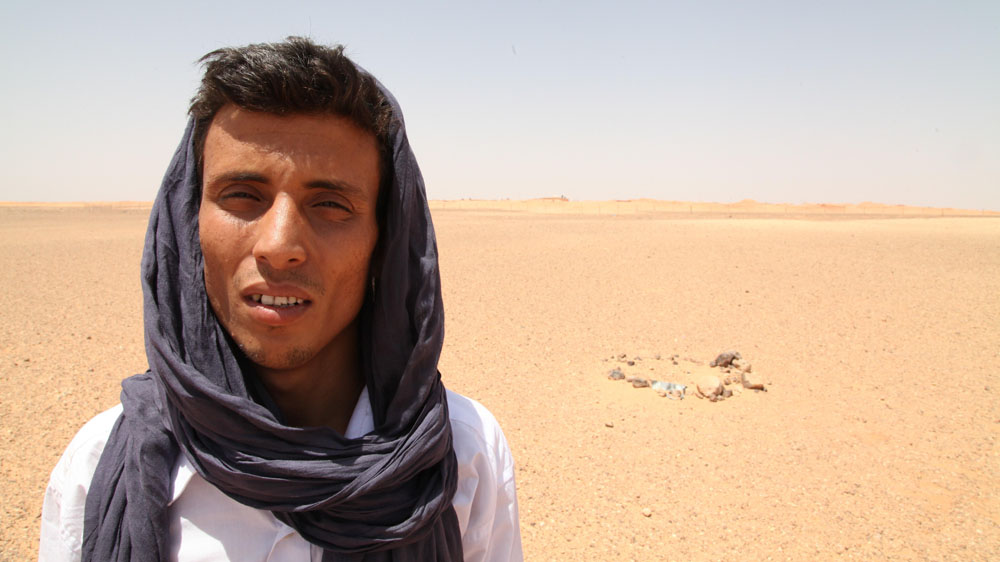 Habiboulah Lamin stands with his back to the Berm guarded by 120,000 Moroccan troops [Hannah McNeish/Al Jazeera]
