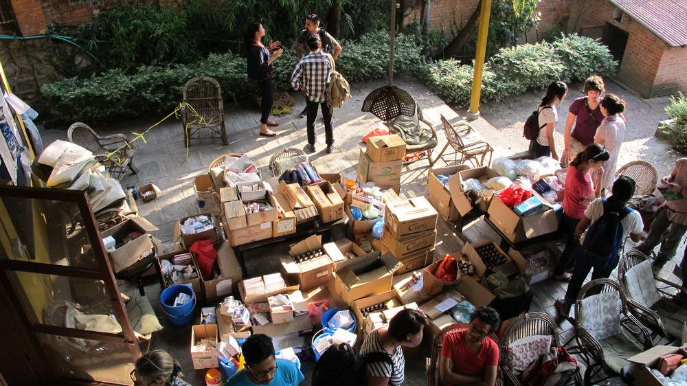 Volunteers stand among medical supplies at The Yellow House in Sanepa, Nepal [Annette Ekin/Al Jazeera]