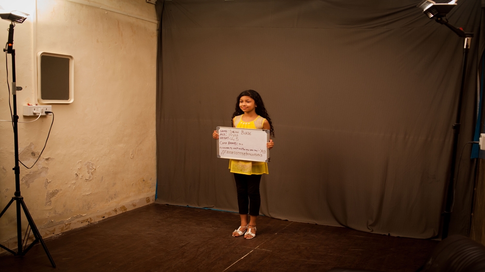 Ten-year-old Saloni Burde holds a board stating her name, age and height during an audition for a chocolate commercial in a studio in Mumbai [Karen Dias]