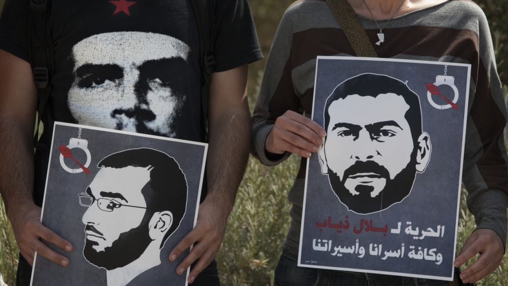 Protesters hold posters depicting the faces of Palestinian prisoners on hunger strike, Thaer Halahleh, left, and Bilal Diab, right [AP]