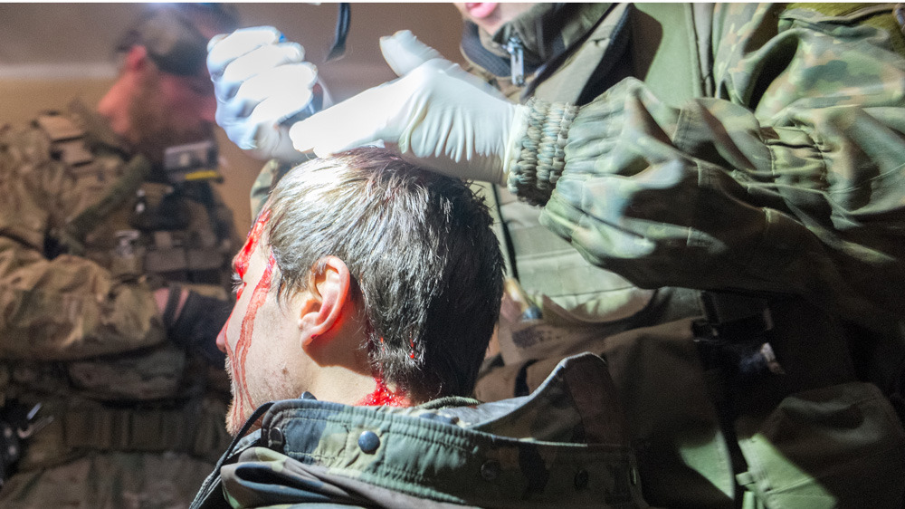 A paramedic attends to one of Azov's European fighters after he sustained an injury while on a mission in Shyrokyne [Christopher Allen/Al Jazeera]