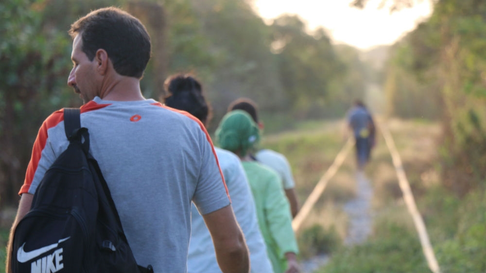Israel de la Rosa and a group of Cuban migrants walk along the railway, hiding from migration authorities [Amparo Rodriguez/Al Jazeera]
