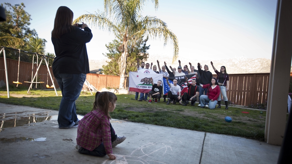 Jeff Hall’s wife Krista takes a picture of National Socialist Movement members as they chant and make Sieg Heil gestures in the garden of her home in Riverside, California. [Julie Platner]
