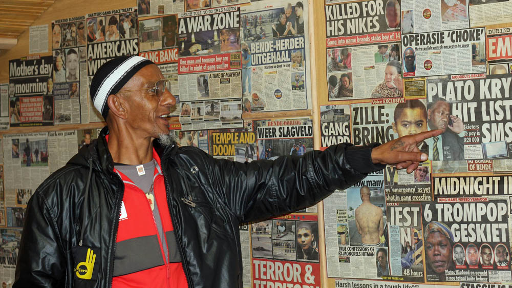 Khiyaam Frey, at the Ceasefire office, shows news clippings detailing gang violence [Dariusz Dziewanski] 