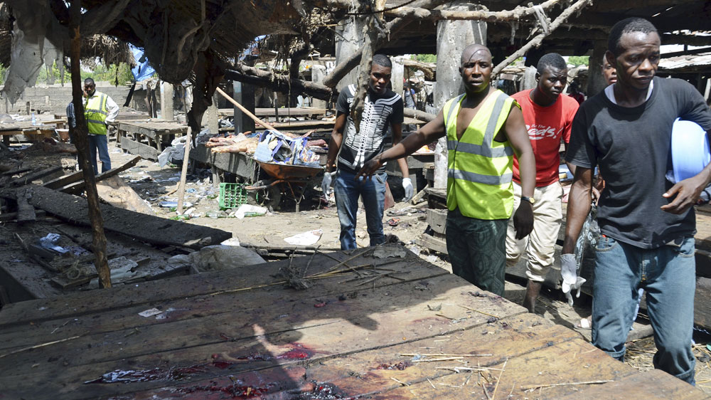 Rescue workers at the site of a suicide bomb attack at a market in Maiduguri , Nigeria