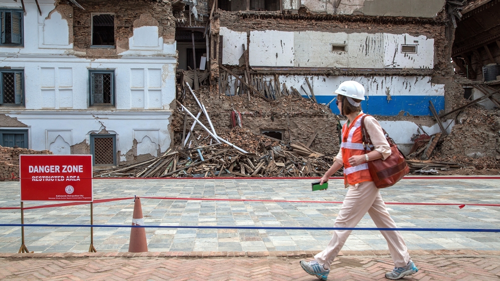 A delegate walks in front of a damaged palace during their visit to Basantapur Durbar Square ahead of International Donors'' Conference [Getty]