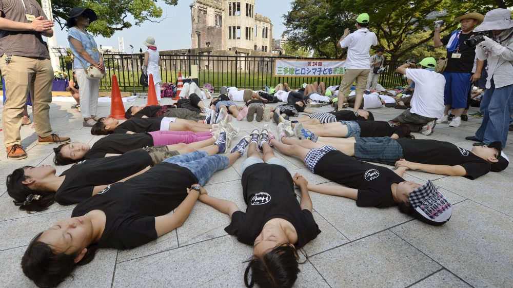  Children perform a die-in in front of the Atomic Bomb Dome at Peace Memorial Park in Hiroshima [Reuters]