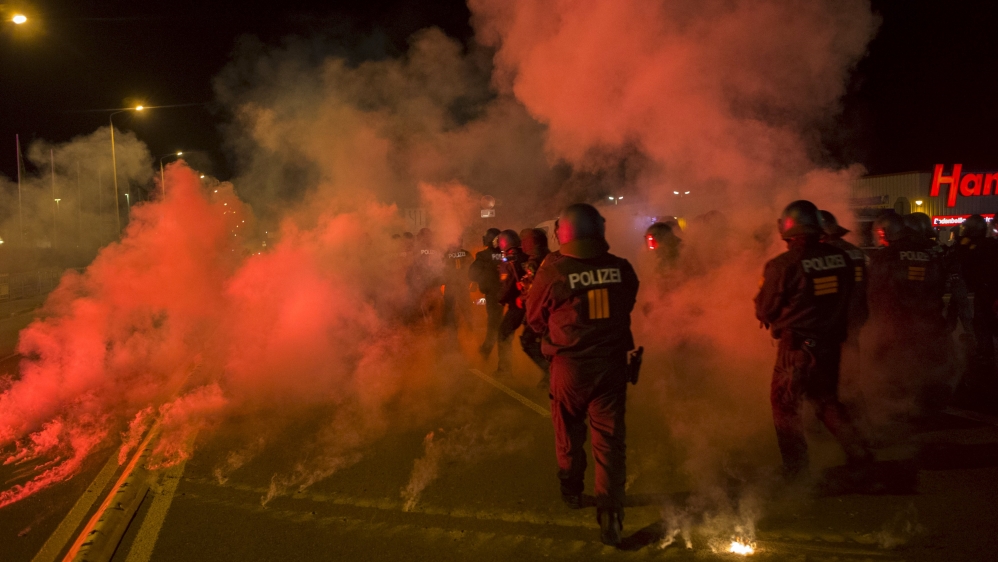 Policemen walk between flares thrown by right wing protesters who are against bringing asylum seekers to an accomodation facility in Heidenau