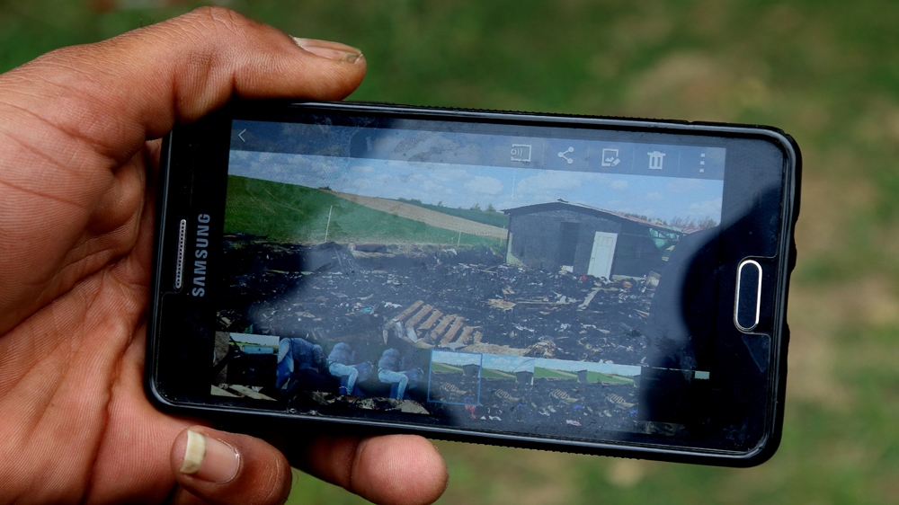 An Eritrean man shows the fire-destroyed camp in Norrent-Fontes [Philip Kleinfeld/Al Jazeera]