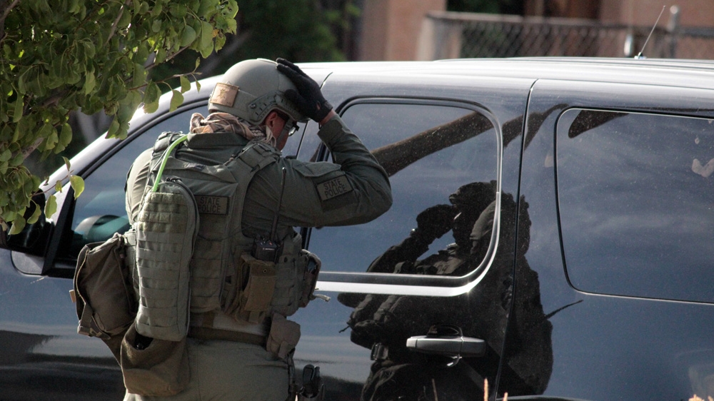 An Albuquerque's SWAT team member uses a police SUV as a mirror to adjust his helmet during a standoff with a mentally ill suspect in June 2015 [Andy Beale/Al Jazeera]