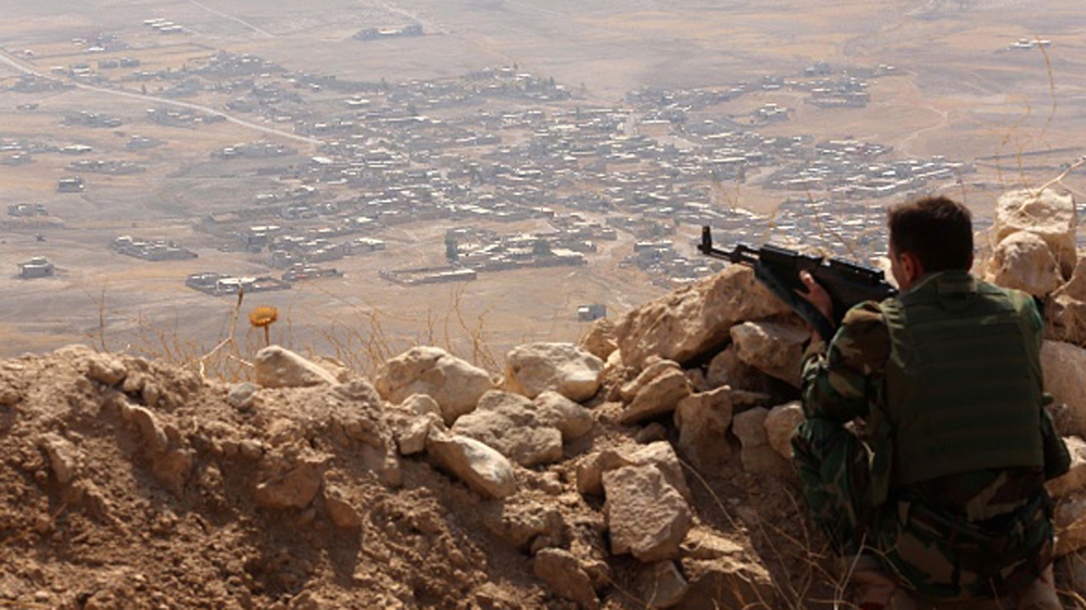 An Iraqi Kurdish Peshmerga fighter monitors his surrounding from the top of Mount Zardak, about 25 kilometres east of Mosul [AFP]