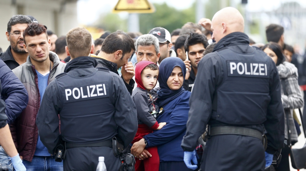 German policemen watch as migrants are taken off a train at a border station in Freilassing