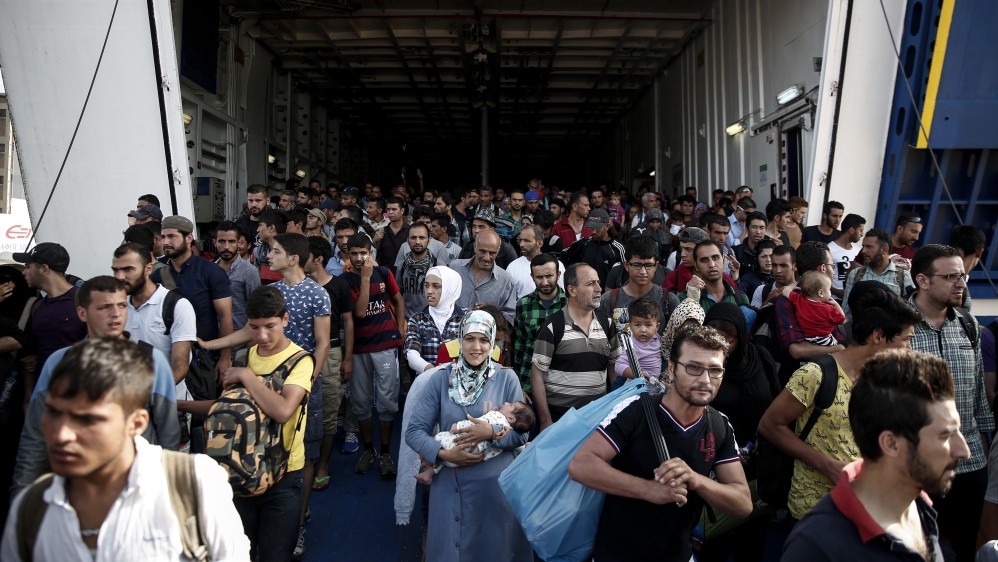 Migrants and refugees disembark from a ferry