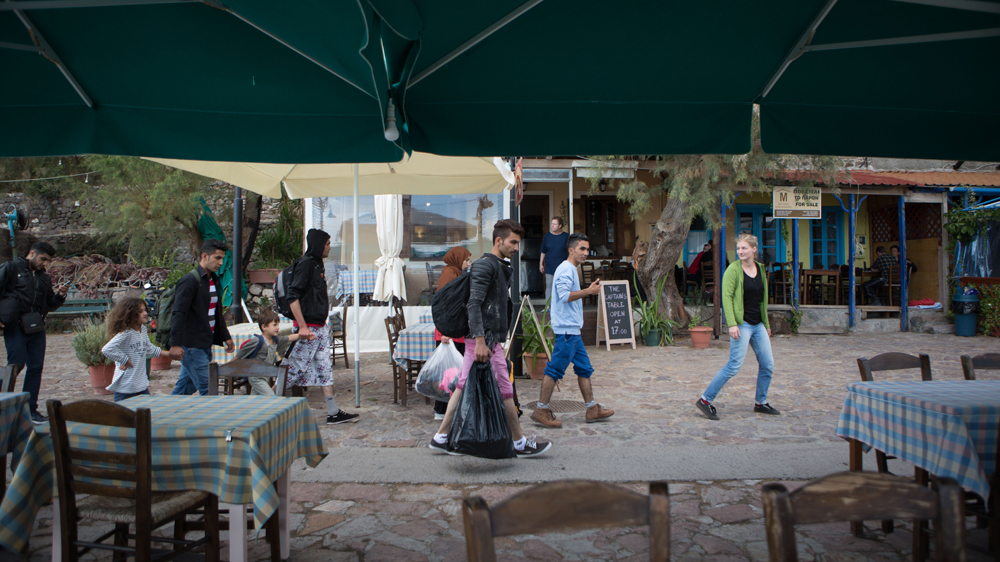 One of McRostie's volunteers leads a group of refugees through restaurants and cafes in the port of Molyvov, Greece. [Andrea DiCenzo/ Al Jazeera]
