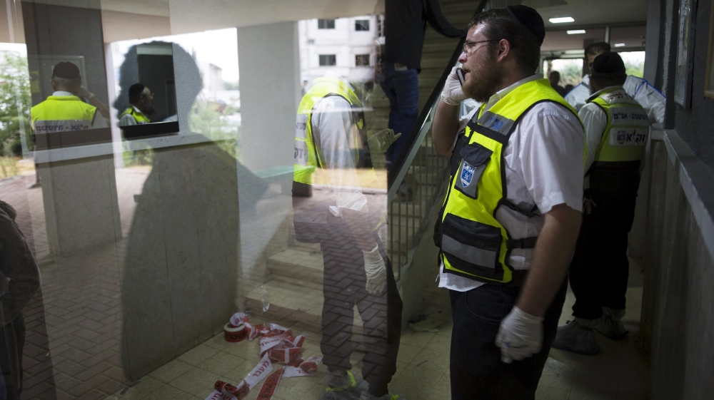 Israeli members of the Zaka Rescue and Recovery team are seen through a building''s window as they work at the scene of a stabbing attack in Kiryat Gat