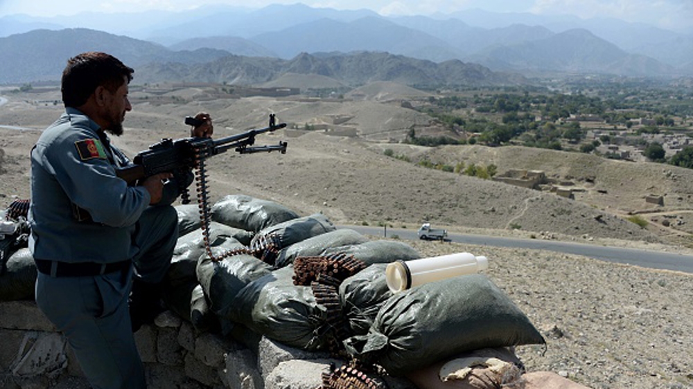 An Afghan security force member stands at a checkpoint, set alight by ISIL fighters during overnight clashes between Afghan forces and ISIL groups, in eastern Nangarhar province [Getty]