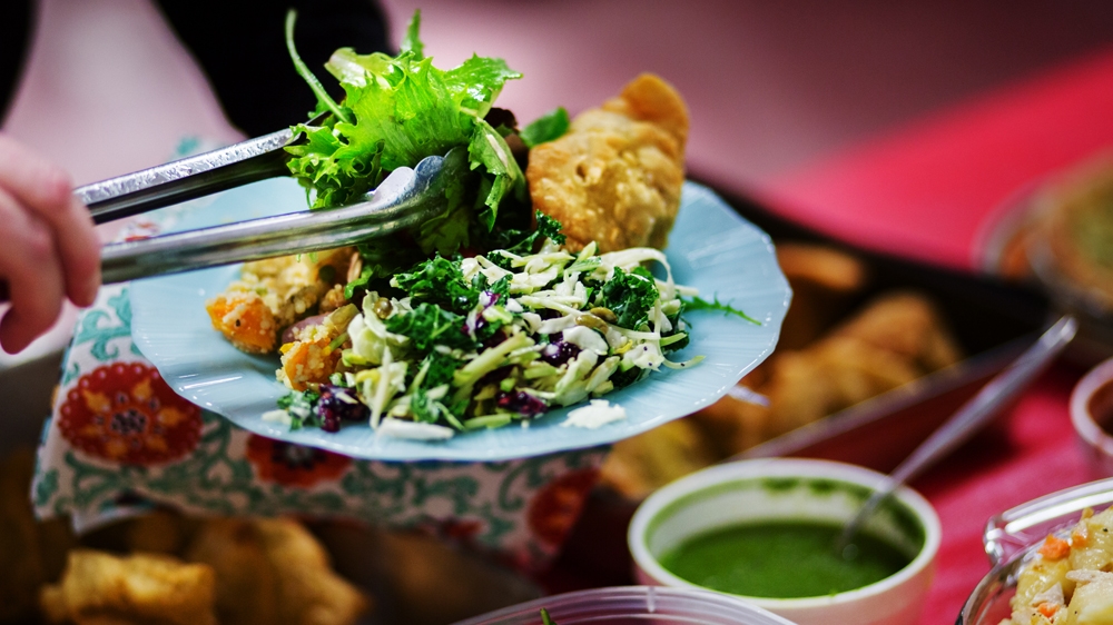 At the potluck meeting, the group breaks bread together to celebrate their success, but more importantly, to make plans for the arriving Syrian refugee families [Ryan Edwardson/Al Jazeera]