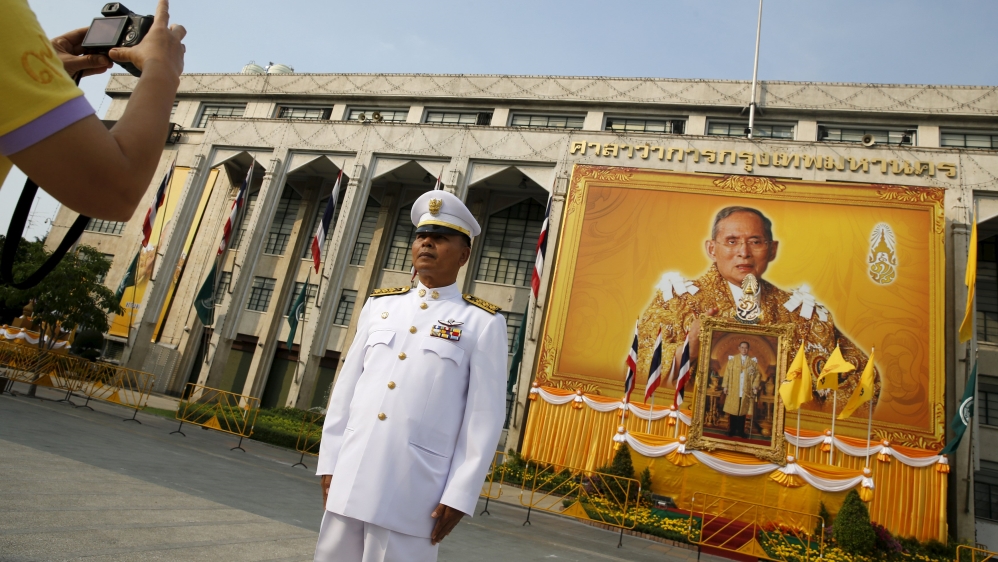 An army official takes a picture of him in front of of Thai King Bhumibol Adulyadej pictures as people gather to mark his 88th birthday in Bangkok