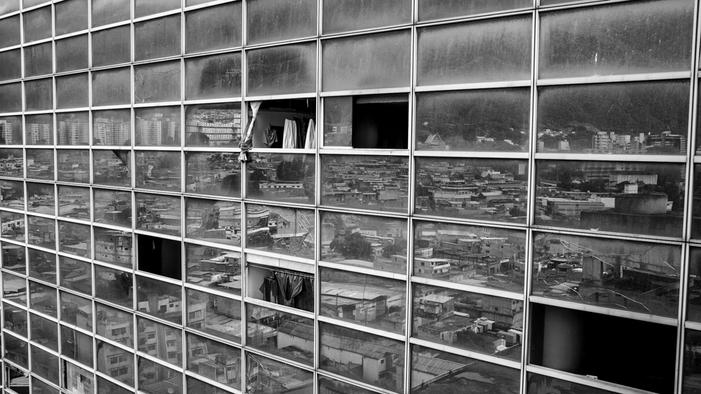 The city below can be seen reflected in the windows of the north facade, the only part of the building that still has its original design [Alejandro Cegarra/Al Jazeera]