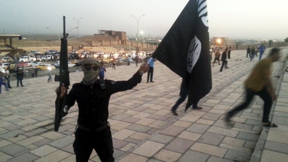 File photo of a fighter of ISIL holding a flag and a weapon on a street in Mosul