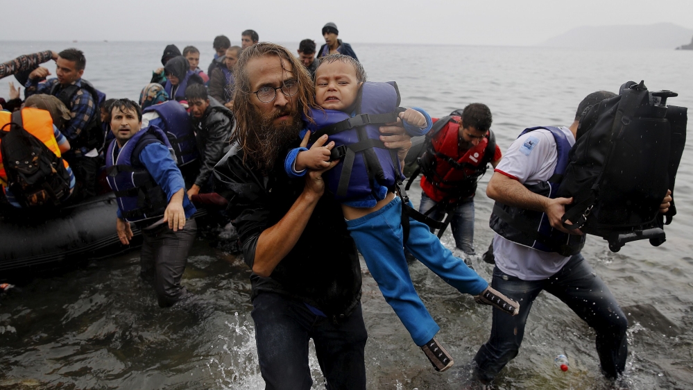 File photograph shows a volunteer carrying a Syrian refugee child off an overcrowded dinghy at a beach after the migrants crossed part of the Aegean Sea from Turkey to the Greek island of Lesbos